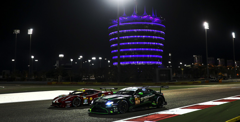 Two World Endurance Championship cars passing the illuminated tower at the Bahrain International Circuit