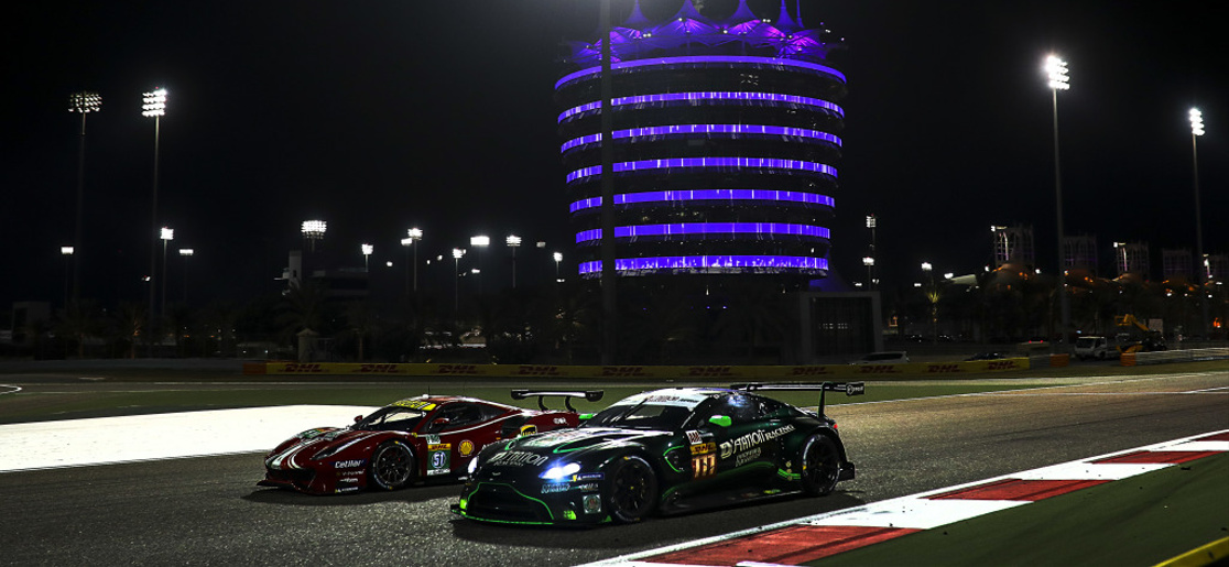 Two World Endurance Championship cars passing the illuminated tower at the Bahrain International Circuit