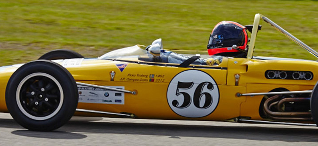 A yellow single-seater car with the number 56 on the side driving at the Nurburgring cicuit
