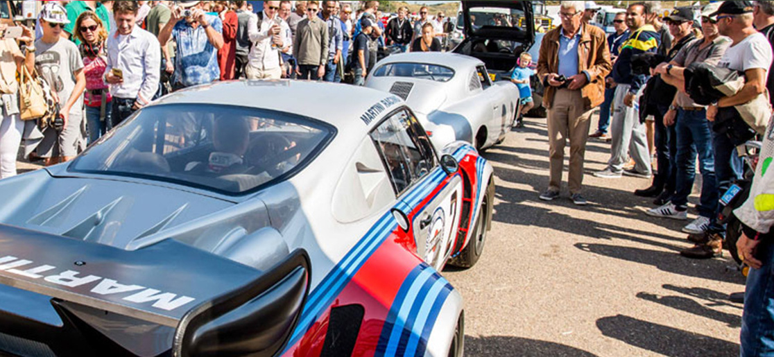 Fans admiring a silver Porsche as it drives towards the Zandvoort circuit